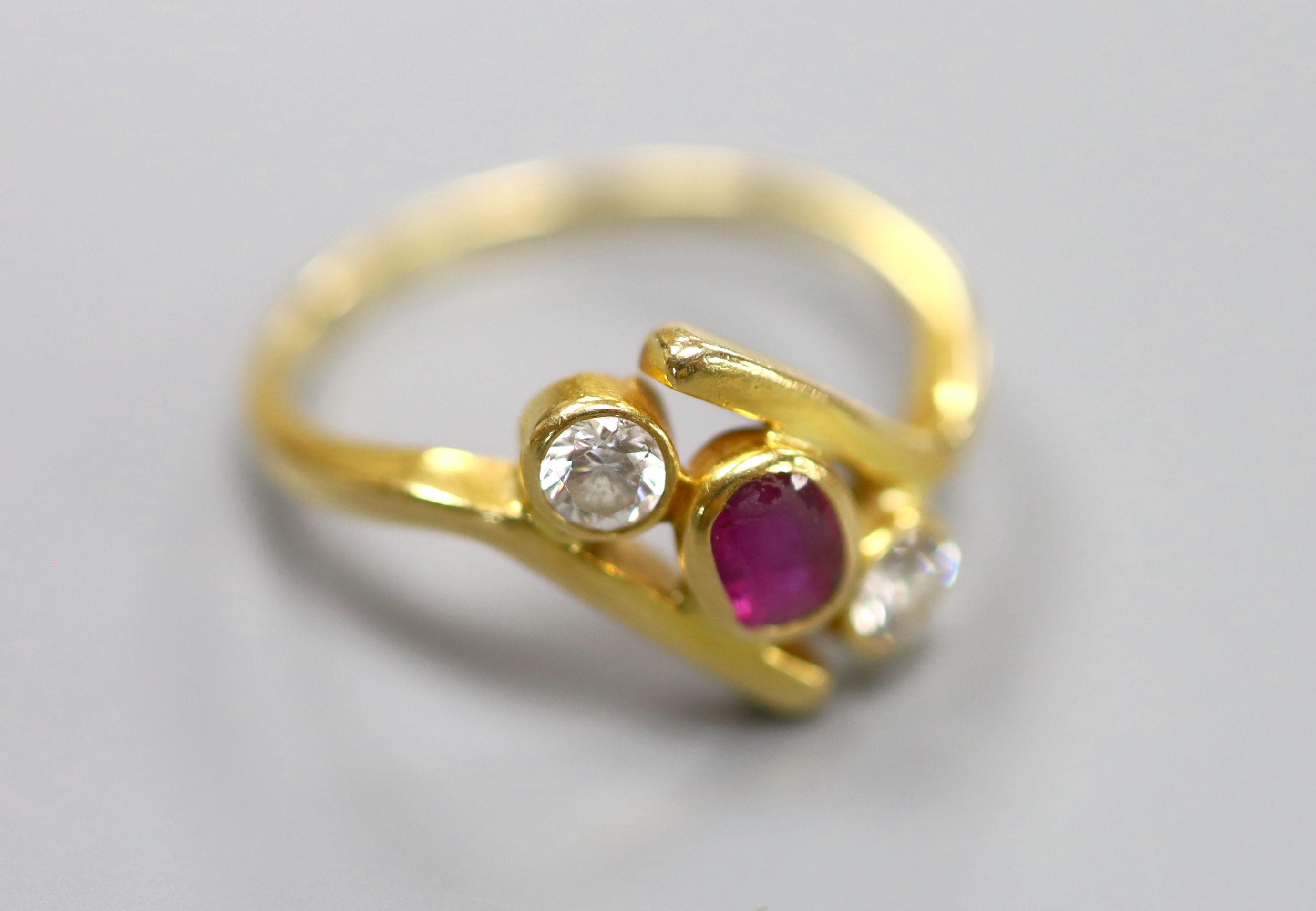A 750 yellow metal, ruby and diamond three stone crossover ring, size P, gross 4 grams.